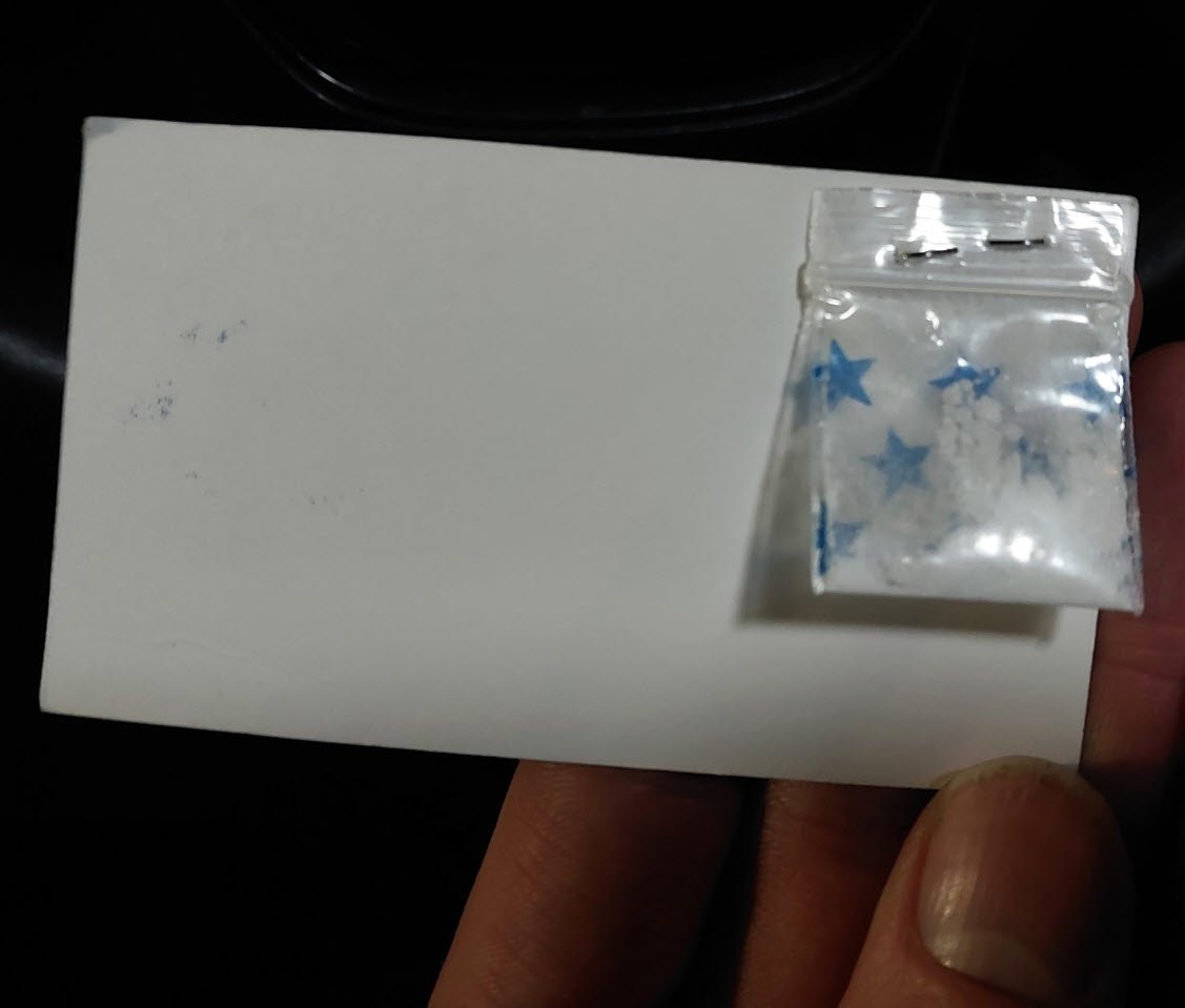 Business card with stapled bag of cocaine